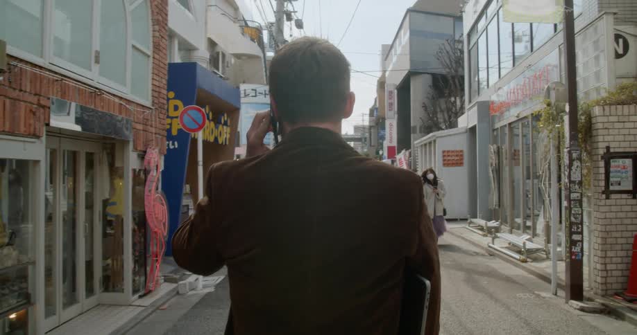 Man talking on cell phone walking through streets in japan
