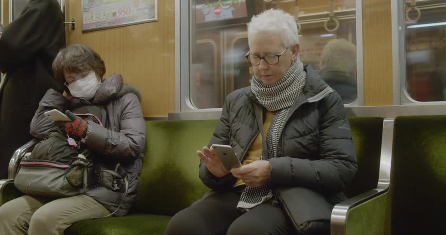 People scroll on their phones while riding a subway