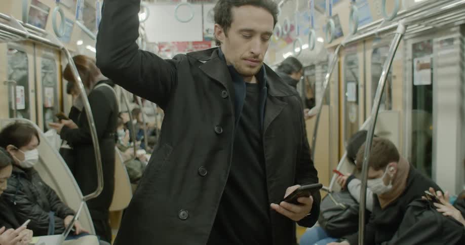 Man using pivoted grab handles stands on a subway train