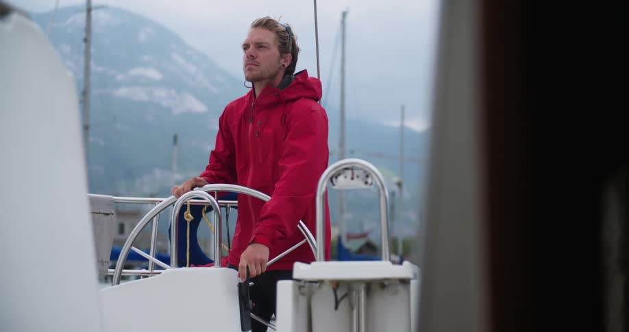 A man pilots a boat near mountains