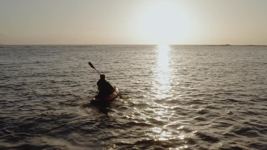 A person in a kayak paddling towards the horizon