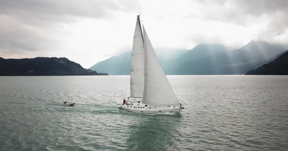 A boat sailing across a body of water with a smaller boat following in its wake