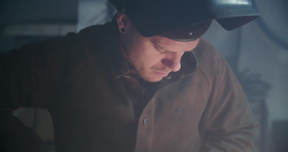 A man looks down as he welds