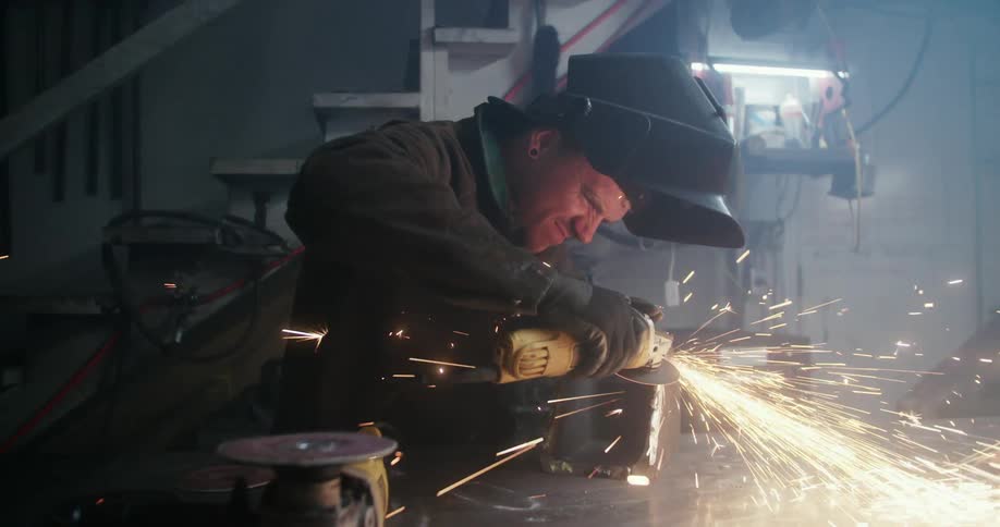 Man uses power tool to grind metal box