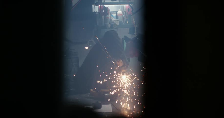 Sparks fly as a welder grinds a piece of metal