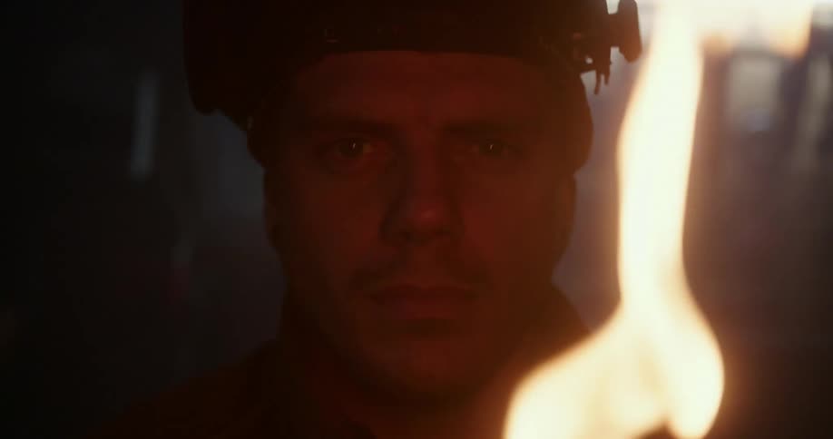 A man with a welding mask staring as fire is in front of him