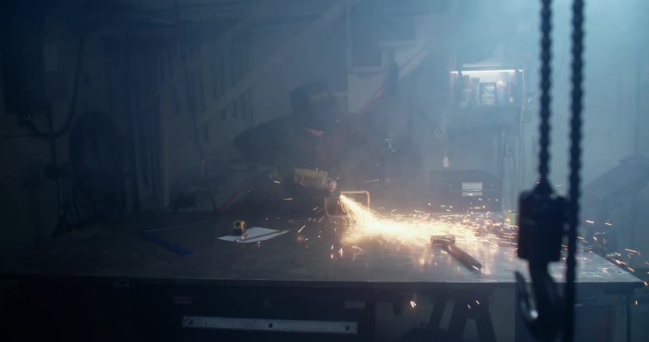 A man uses a hand saw to shave the edge of a metal block