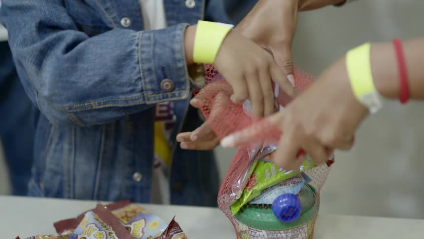 A woman holding a red netted bag while a boy place