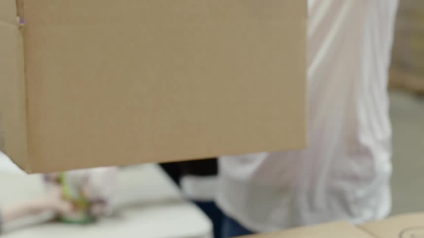 A woman places an empty box on top of two closed boxes
