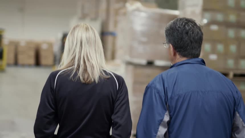 A man and a woman walking in a warehouse