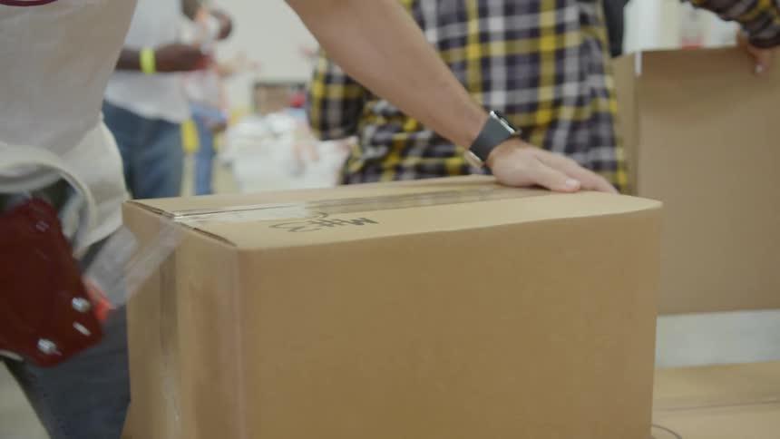 Warehouse workers packing supplies in cardboard boxes