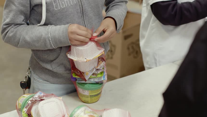 Children packing snacks on net bags in warehouse