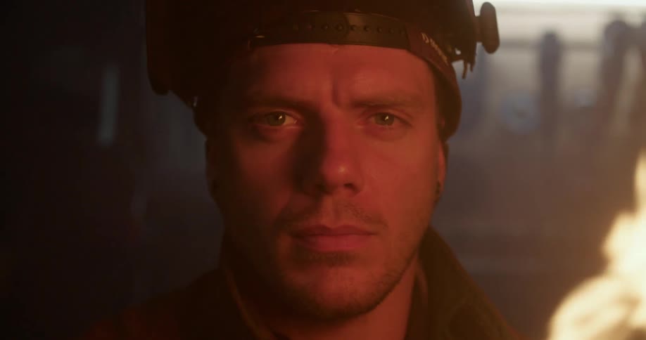 Man stands in darkened room near fire