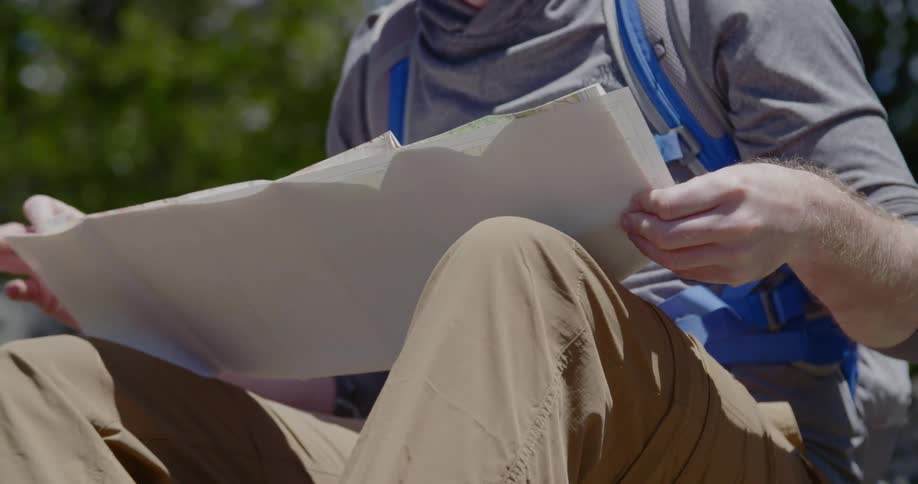A backpacker sits and unfolds a paper map