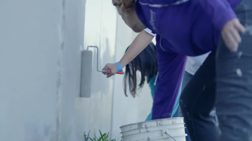 People paint a wall outside