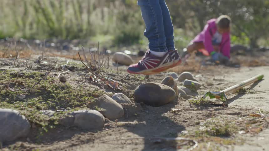 Kid jumping on a rock in backyard