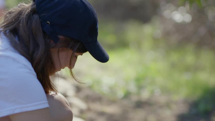 Woman in baseball cap working outdoors in dirt