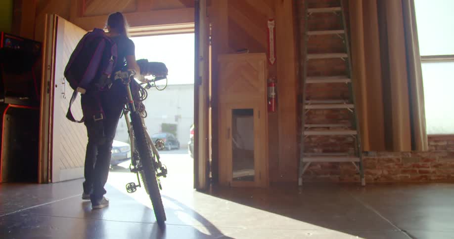 A girl walks her bike out of a building