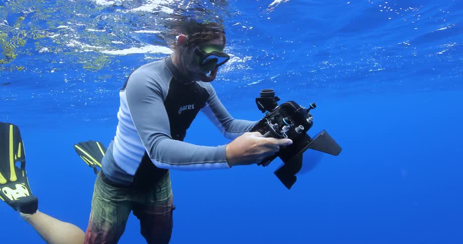Man swimming underwater with camera