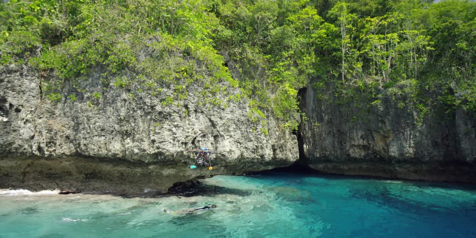 A drone follows a snorkeler as they swim in a lagoon