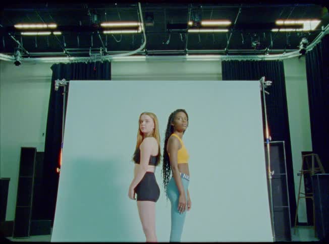 Two women pose back to back in photo studio