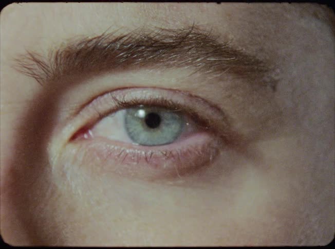 Close up of blinking green eye while lights flash