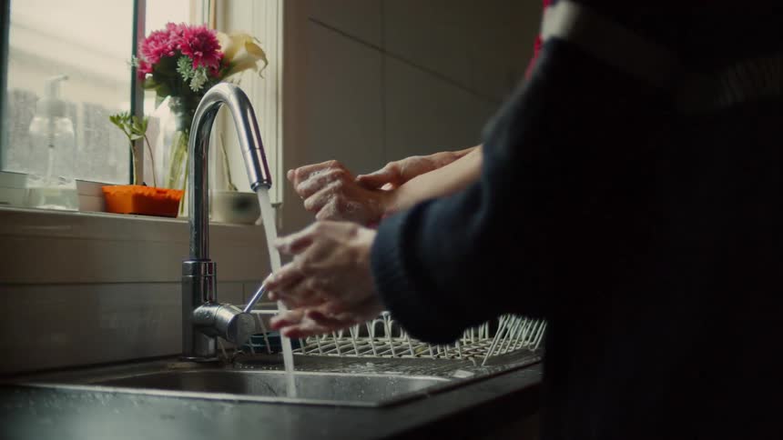 Man and woman wash their hands with soap due to coronavirus in the kitchen