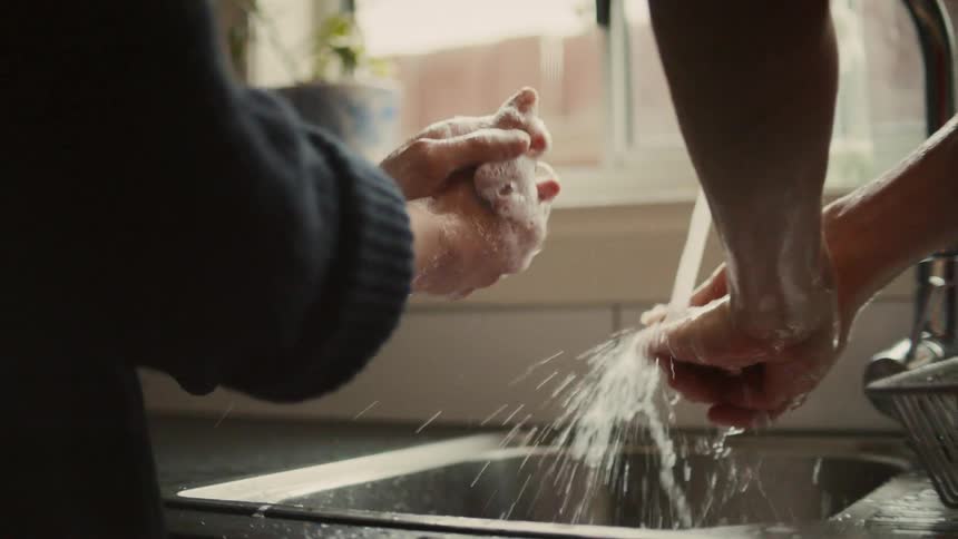 Two people wash their hands on the kitchen sink