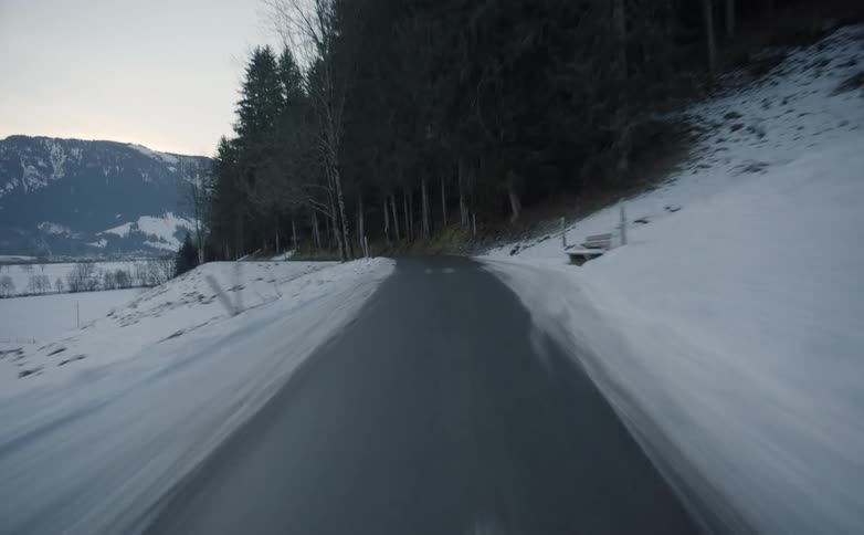 Driving on a road with snow on both sides near a forest