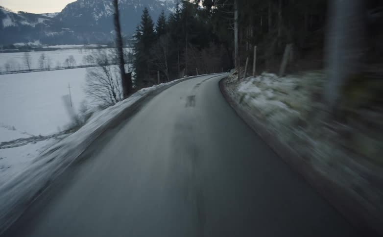 Vehicle drives along the winding narrow road in the snowy hills