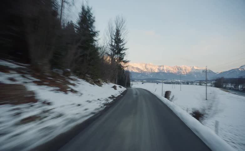 Vehicle drives along the narrow winding road in the snowy countryside
