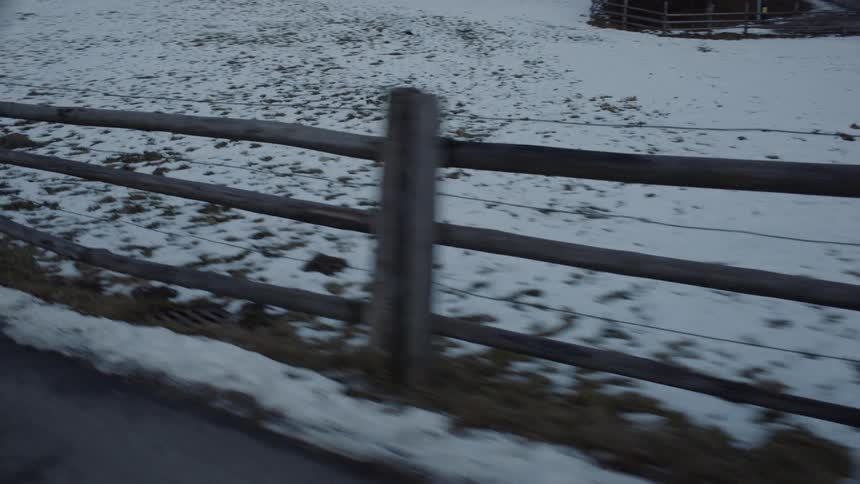 Vehicle drives along the road between the snowy farmlands