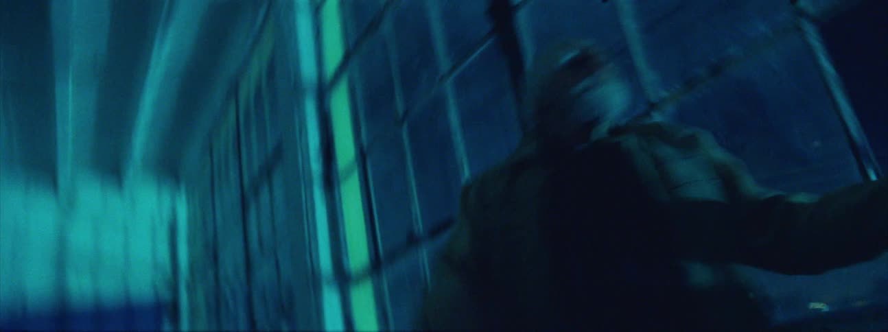 An elderly man waves his arms around chaotically in a hospital hallway