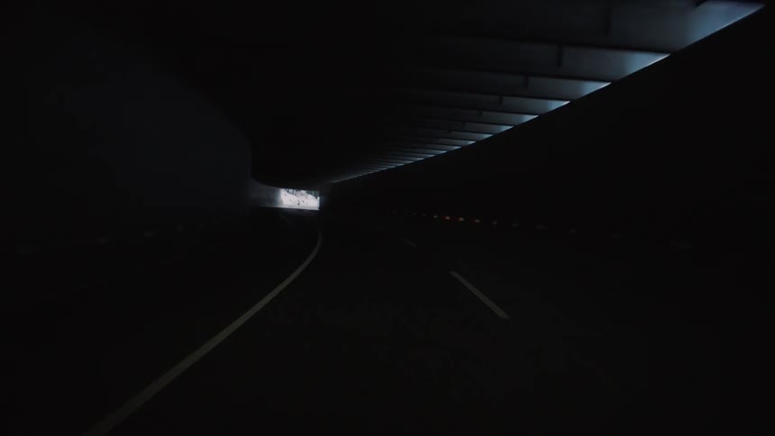 Driving through a long dark tunnel on a mountain road