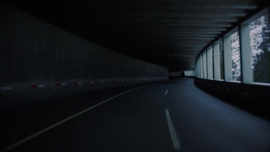 Road goes through the tunnel next to a snowy mountain