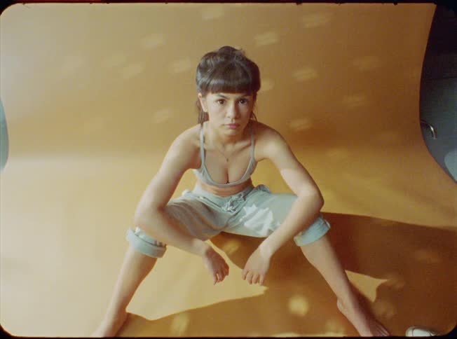 A woman in front of an orange screen staring