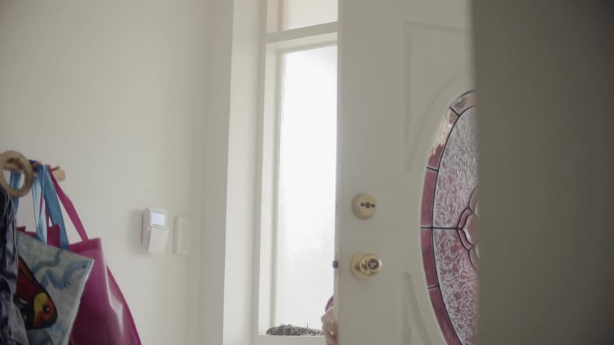 A person wearing a face mask walks out the door of a house