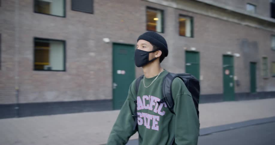 Man wearing face mask walks down empty street wearing a backpack
