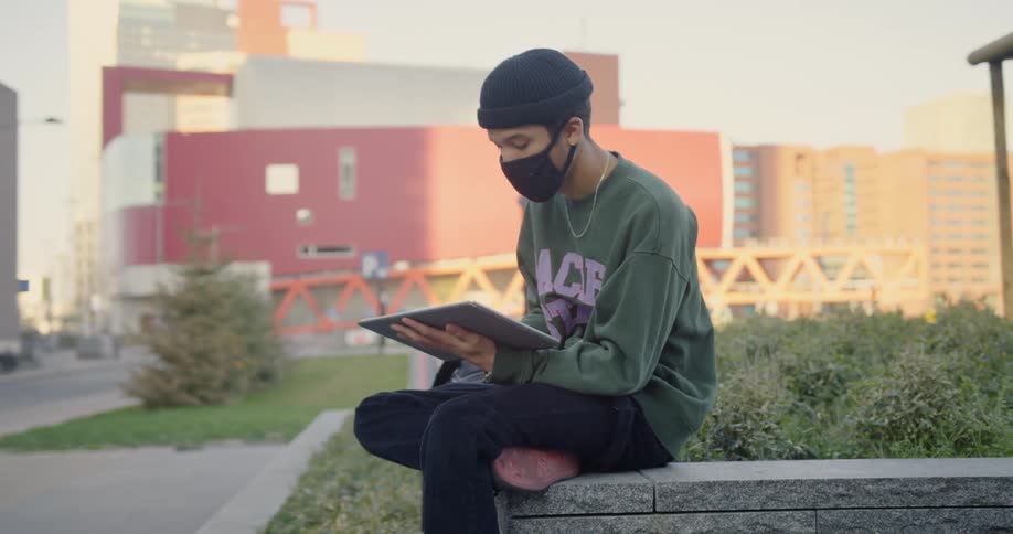 A man in a mask draws on a tablet