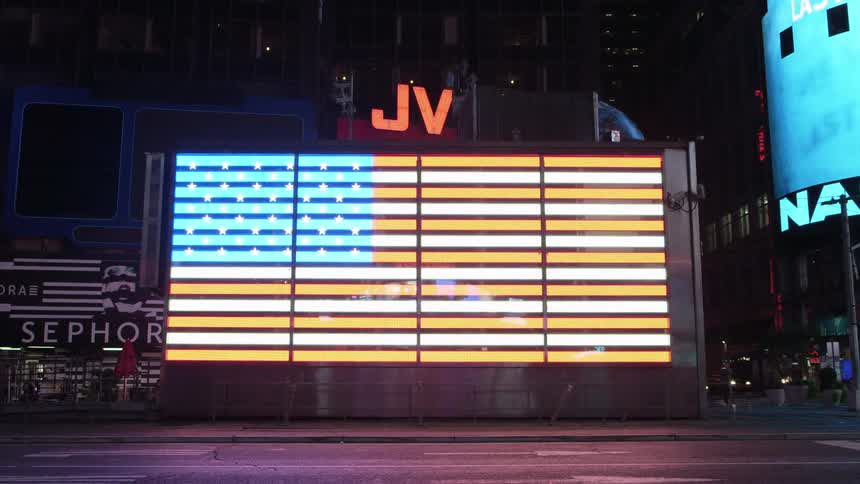 American flag displayed on a screen in the street of a city
