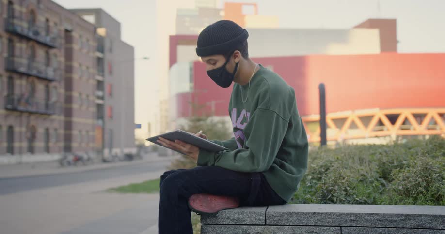 Artist sits on corner of raised flower bed sketching almost empty city street