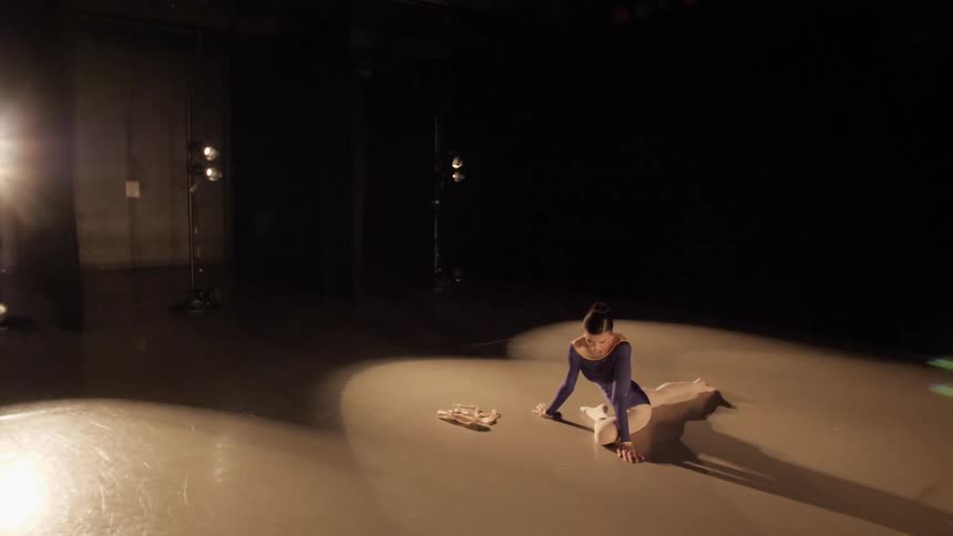 A ballerina stretches on the floor