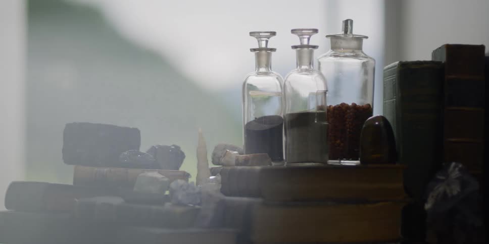Stones books and bottles of powder stacked on a table