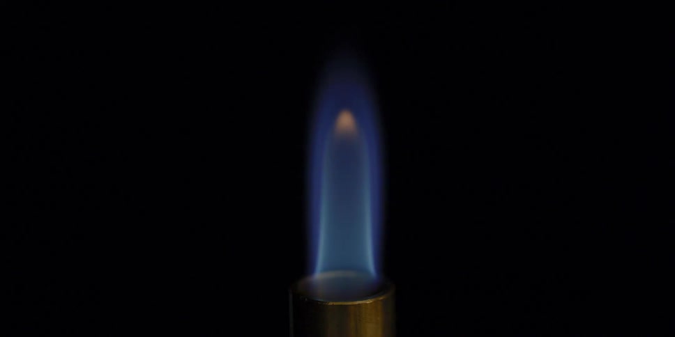 A blue flame with a orange tip coming out of a gold cylinder