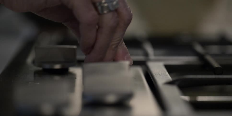A woman turns a dial on a stove