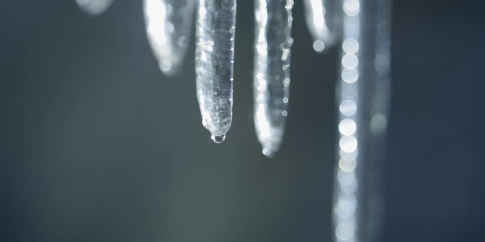 The water slowly drips from the icicle