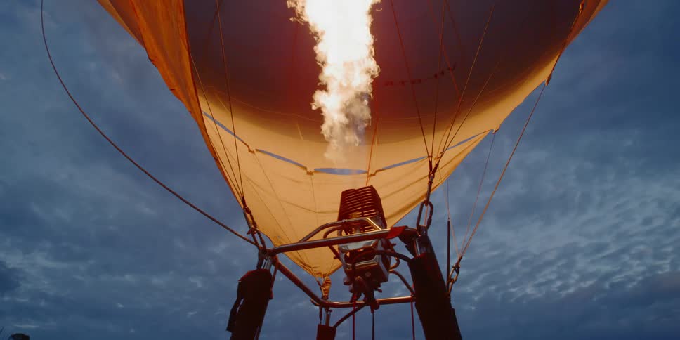 Flame rises and inflates hot air balloon at dusk