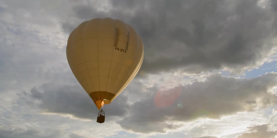 A yellow air balloon floating on a cloudy day