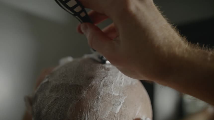 A man is having his head shaved