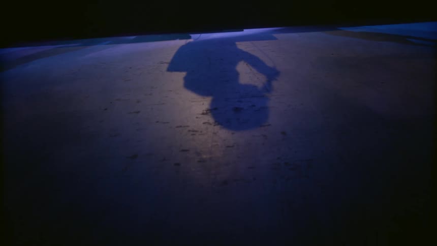 The shadow of a person using a microphone performing on a stage